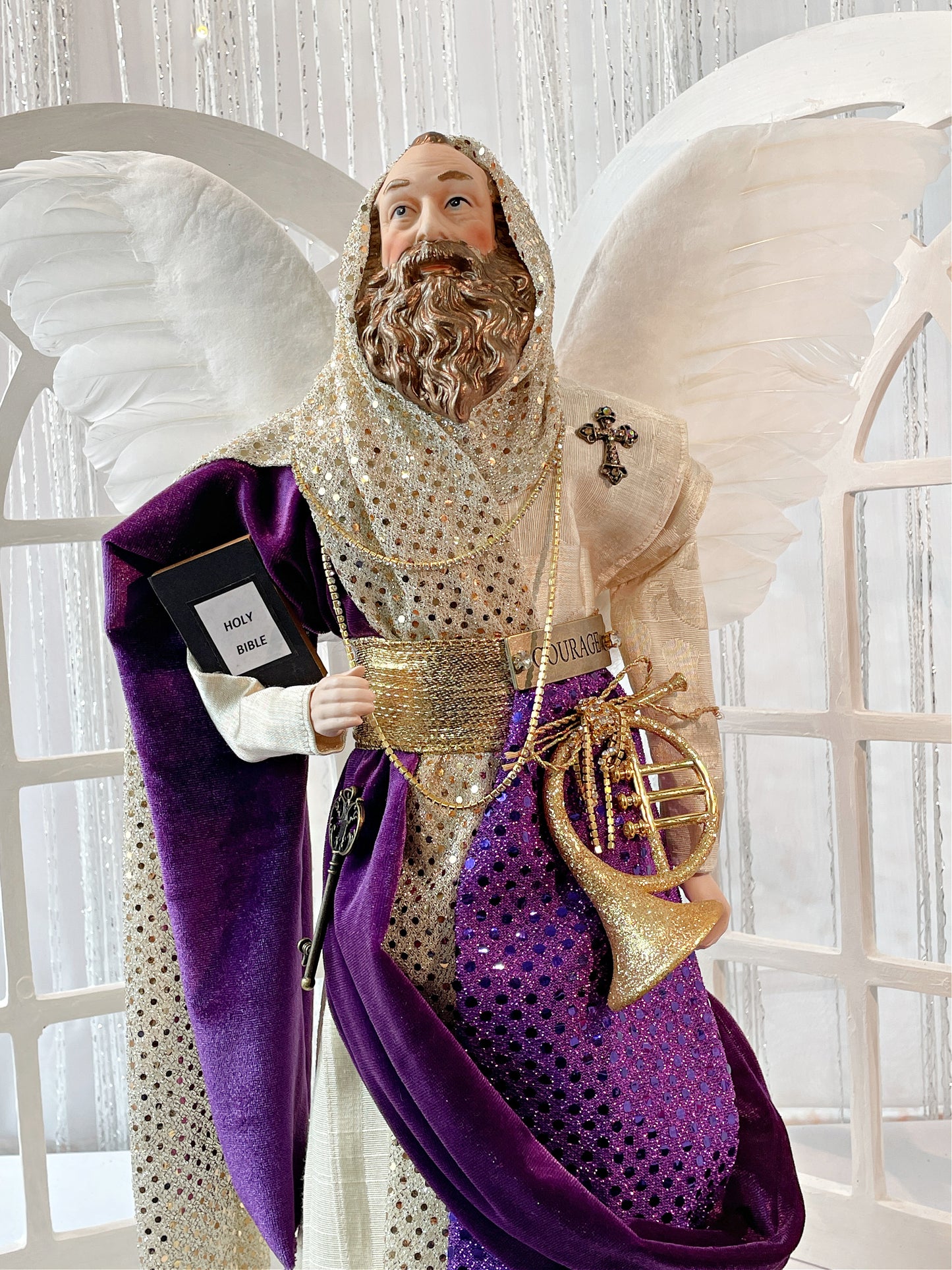 20 Inch tall Male Angel Treetopper  in Ivory, Purple and Gold, he has a horn at his side, a Bible in his arm, a cross on his shoulder and a metal plate at the waist that says courage